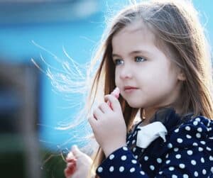 Little girl putting on lip balm