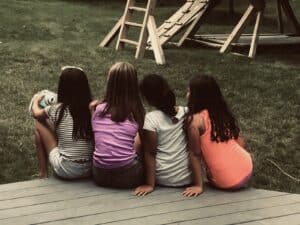 Four girls sitting together playing telephone