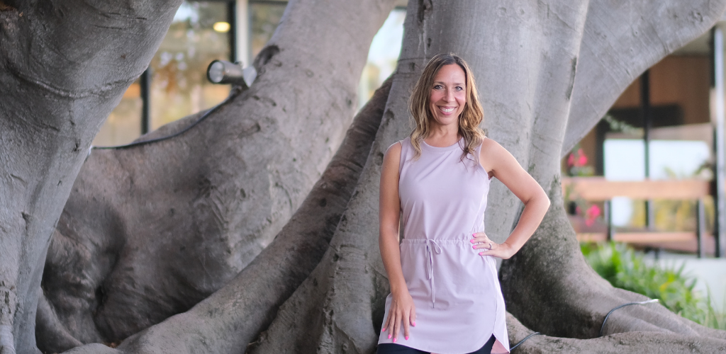 smiling woman on roots of a large tree