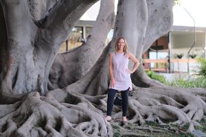 smiling Amy Johnson on roots of a large tree