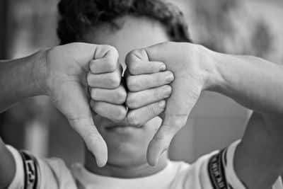 man holding his hands in front of his face with his thumbs down