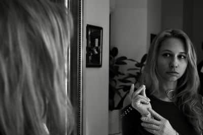 Lady inquisitively looking at herself in the mirror