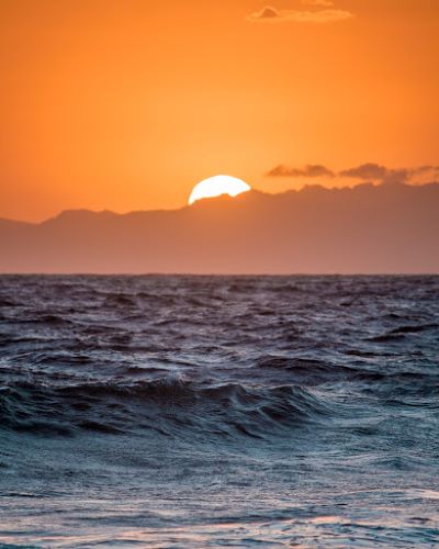 Image of a sunset in an orange sky with the sea in the foreground