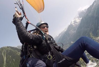 Photo of Change Coach Becky paragliding above mountains