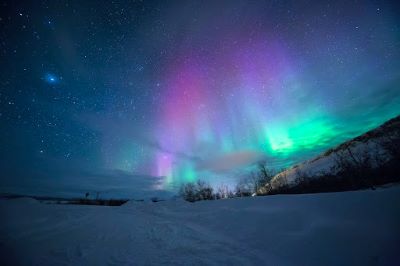 Night time snowy landscape with the Northern Lights and lots of stars in the sky